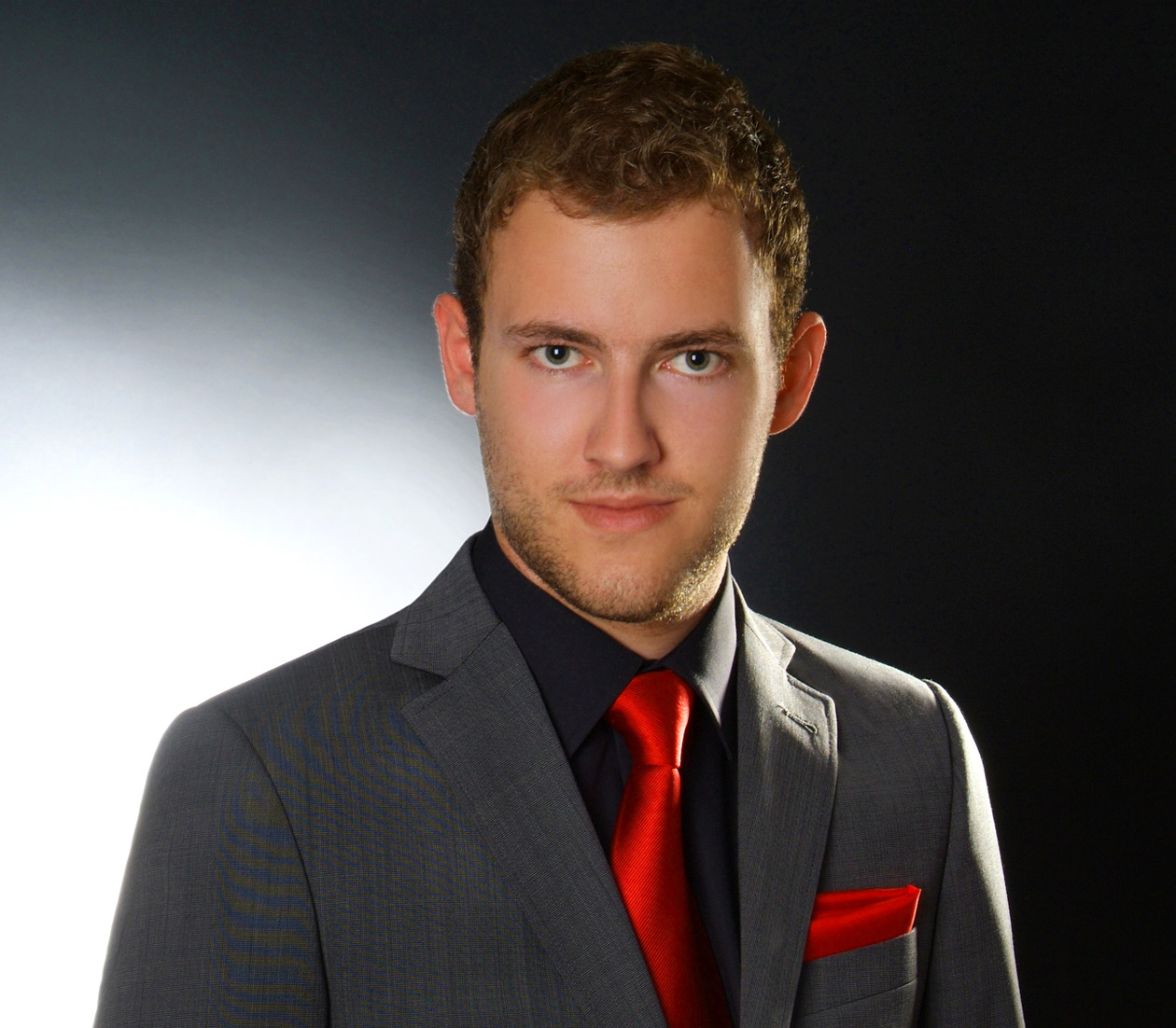 Portrait von Andreas Lenz mit schwarzem Hemd, roter Krawatte, rotem Einstecktuch und grauem Sacko